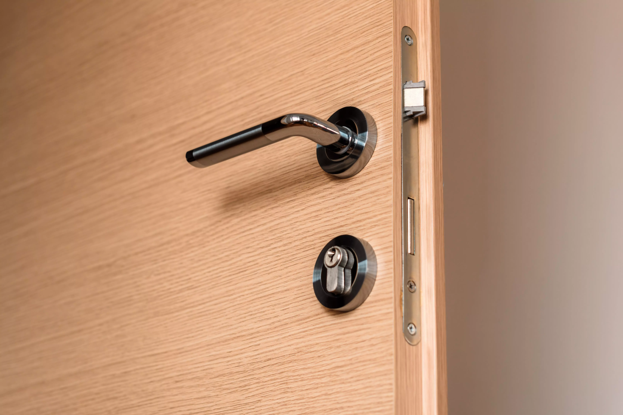 une serrure moderne métallique, dans une porte beige.